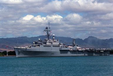 The flagship USS CORONADO (AGF-11), flagship of the Third Fleet, steams through the channel as it departs from the naval station.