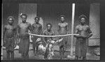 Men with caught fish strung to pole