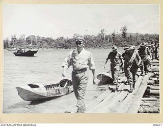 THE JAPANESE NAVAL COMMANDER TAKAHASHI LEADING AN AUSTRALIAN SURRENDER PARTY, MEMBERS OF HEADQUARTERS 2 CORPS, ALONG THE JETTY AT JAPANESE NAVAL HEADQUARTERS, BONIS PENINSULA. THE PREVIOUS DAY THE ..