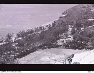 ELA BEACH, NEW GUINEA. 1943-12-29. ELA BEACH SPORTS GROUND. IN THE BACKGROUND ON THE EAST SIDE OF THE PAGA HILL THE OFFICER'S CLUB CAN BE SEEN ON THE WATERS EDGE