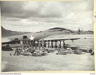 1942-12-07. NEW GUINEA. A 105MM M-3A1 HOWITZER COMPLETE WITH SPARES, TRACTOR AND AMMUNITION IS UNLOADED SOMEWHERE IN THE BATTLE AREA. THE GUN CREW ALSO CAME WITH THE GUN. PICTURE SHOWS THE CARGO ..