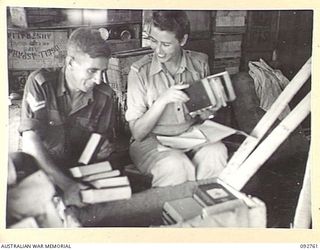 WEWAK AREA, NEW GUINEA. 1945-06-03. MISS BOWN, RED CROSS SOCIETY REPRESENTATIVE (1), AT 104 CASUALTY CLEARING STATION, WHO IS IN CHARGE OF THE LIBRARY AND HOBBIES IN THE AREA, SORTING NEWLY ARRIVED ..