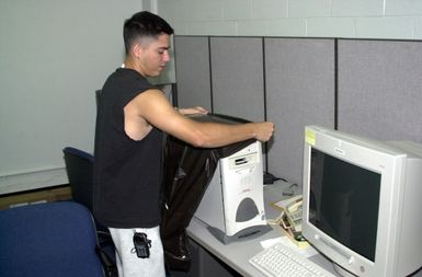 US Air Force (USAF) STAFF Sergeant (SSGT) Mark Rose, 36th Communications Squadron (CS) places a plastic covering over the computers in the visual information center, during typhoon preparedness as typhoon Chata'an approaches, Andersen Air Force Base (AFB), Guam