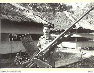 LAE, NEW GUINEA. 1944-07-05. VX58873 CAPTAIN E. MEIER, STAFF CAPTAIN, DEPUTY DIRECTOR OF ORDNANCE SERVICE, NEW GUINEA FORCE, BESIDE A CAPTURED JAPANESE DUAL PURPOSE (ANTI-AIRCRAFT AND AIR-TANK) GUN