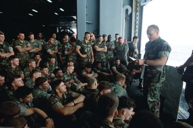 Marines of the 22nd Marine Expeditionary Unit (22nd MEU) gather in the hangar bay aboard the amphibious assault ship USS SAIPAN (LHA-2) for a briefing on the situation in Monrovia, Liberia, and the rules of engagement governing their mission once ashore. The SAIPAN is on station off the coast of Liberia for Operation Sharp Edge