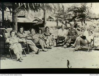 Aitape, New Guinea. 1945-01. Sisters of the 2/11th Australian General (2/11AGH) relax on deck chairs in the sun outside their Mess. Left to right: SFX3058 Sister T.L. Umpherston, SFX26392 Sister ..