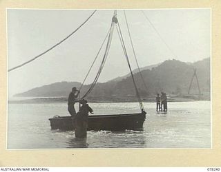 DANMAP RIVER, NEW GUINEA. 1945-01-05. A COLLAPSABLE ASSAULT BOAT ATTACHED TO PULLEYS OF A FLYING FOX BUILT ACROSS THE RIVER MOUTH BY TROOPS OF THE 2/14TH FIELD COMPANY, TO TRANSPORT MATERIALS AND ..