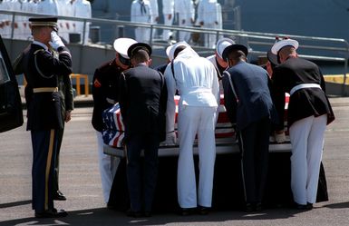 The flag-draped casket of the Unknown Serviceman of the Vietnam Era is placed on the pier by a joint service honor guard in preparation for a wreath-laying ceremony. The casket will be transported to California aboard the frigate USS BREWTON (FF 1086), and then transferred to Arlington National Cemetery for interment at the Tomb of the Unknowns