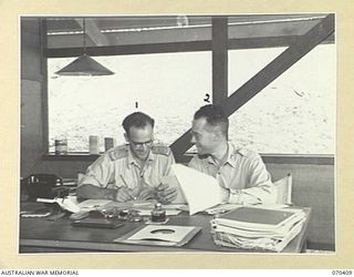 PORT MORESBY, PAPUA, NEW GUINEA, 1944-01-14. CAPTAIN ROBIN WOOD (1) THE STATION SUPERVISOR OF THE AUSTRALIAN BROADCASTING COMMISSION'S RADIO STATION 9PA, AT A MORNING PROGRAM CONFERENCE WITH ..