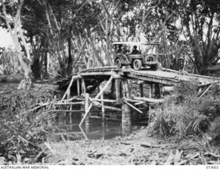 MADANG, NEW GUINEA. 1944-04-25. A JEEP, MODIFIED TO CARRY AN ADDITIONAL LOAD, CROSSES A BRIDGE OVER THE WAGOL RIVER ON THE MADANG - ALEXISHAFEN ROAD. THE BRIDGE WAS ABANDONED INTACT BY THE JAPANESE