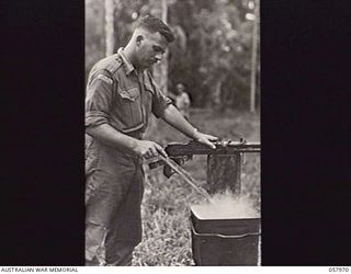 LAE, NEW GUINEA. 1943-10-04. NX9706 WARRANT OFFICER 1 C. T. HALMARICK, PHOTOGRAPHER, MILITARY HISTORY SECTION, WASHES HIS CLOTHES IN THE BOILER AT THE 5TH AUSTRALIAN DIVISION HEADQUARTERS