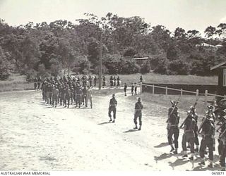 HERBERTON, QLD. 1944-04-25. PERSONNEL OF HEADQUARTERS, 6TH DIVISION, LED BY THE BAND OF THE 2/2ND INFANTRY BATTALION, MARCHING ALONG THE MAIN STREET TO THE WAR MEMORIAL TO TAKE PART IN THE ANZAC ..