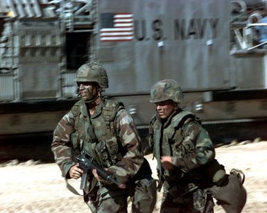 Two US Marines run for positions after disembarking a Landing Craft Air Cushioned (LCAC) from the USS ESSEX (LPH 9) (not shown) during RIMPAC '96 taking place at Pacific Missile Range Facility, Barking Sands, Kauai, Hawaii