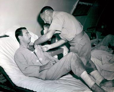 Photograph of Admiral Raymond A. Spruance, Commander of the Fifth Fleet, Pinning a Purple Heart on Clarence E. McElroy, Who is a Survivor of the Cruiser USS Indianapolis (CA-35) at Guam