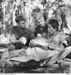 PAPUA, NEW GUINEA. 1942-10. JAPANESE PRISONER CAPTURED NEAR NAURO. HE HAD BEEN OVERWORKED AND WAS NEARLY STARVING WHEN TAKEN PRISONER. HE IS SEEN BEING CARED FOR BY AUSTRALIAN STRETCHER BEARERS