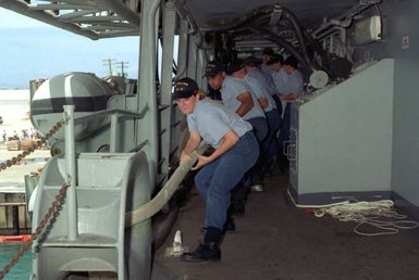 Line handlers of the submarine tender USS HOLLAND (AS-32) pull in mooring lines in preparation for the ship to get underway for a 45 day