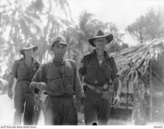 BABIANG AREA, NEW GUINEA, 1944-11-18. A JAPANESE SERGEANT, CAPTURED BY THE 2/10 COMMANDO SQUADRON AT SUAIN IN A WEAKENED CONDITION, RECEIVES AN ESCORT TO ALLIED TRANSLATOR INTERROGATION SECTION ..