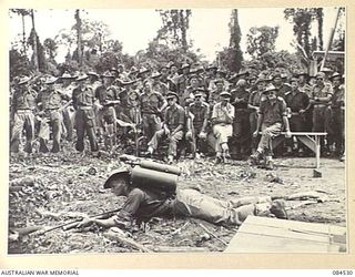 BOUGAINVILLE, SOLOMON ISLANDS. 1944-12-21. AN OPERATOR AT HEADQUARTERS 3 DIVISION DEMONSTRATING THE PRONE POSITION FOR FIRING THE UNITED STATES FLAME THOWER M1A1 DURING A COURSE ARRANGED BY THE 132 ..