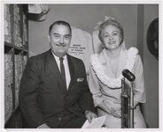 Priest, right, with Jack Benson, commentator for KGMB-TV, with Bishop National Bank of Hawaii bags in background, on May 6, 1959