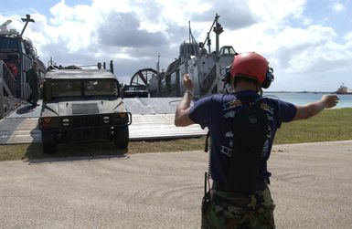 US Navy (USN) Signalman Richard Cote, Beach MASTER Unit One, Sasebo, Japan, guides a US Marine Corps (USMC) High-Mobility Multipurpose Wheeled Vehicle (HMMWV) off a USN Landing Craft, Air Cushioned (LCAC) on to the beach at Inner Apra Harbor, Guam. Beach MASTER Unit One is taking part in Exercise TANDEM THRUST 2003