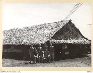 CAPE WOM, NEW GUINEA. 1945-09-29. THE HUT USED AS THE AUSTRALIAN ARMY EDUCATION SERVICE CENTRE, HEADQUARTERS 6 DIVISION. SHOWN, STAFF OF THE CENTRE