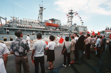 Spactators wave red flags, as naval personnel of the visiting Chinese training vessel ZHENG HE man the rail