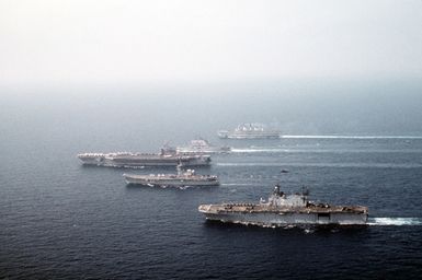 Ships from four nations sail in formation during the NATO Southern Region exercise Dragon Hammer '90. The ships are, from front: the amphibious assault ship USS SAIPAN (LHA-2), the Spanish aircraft carrier SPS Principe de Asturias (R-11), the nuclear-powered aircraft carrier USS DWIGHT D. EISENHOWER (CVN-69), the Italian light aircraft carrier ITS GIUSEPPE GARIBALDI (C-551) and the British light aircraft carrier HMS INVINCIBLE (R-05)