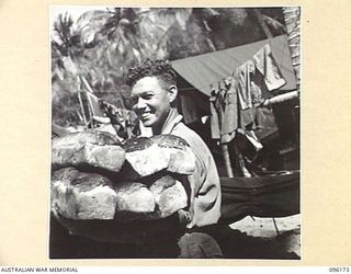 BRANDI, NEW GUINEA, 1945-09-07. SERGEANT C.J. CAMP, 35 INFANTRY BATTALION, CARRYING IN LOAVES OF BREAD