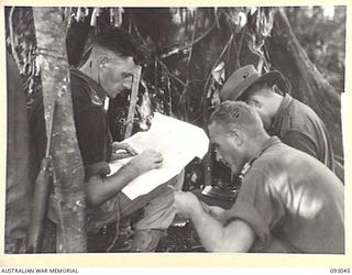 WEWAK AREA, NEW GUINEA, 1945-06-11. LT A.R. BENTLEY, INTELLIGENCE OFFICER, 2/8 INFANTRY BATTALION (1) AND CAPT H.A. COULSTON, OFFICER COMMANDING B COMPANY (2), CHECK AERIAL PHOTOGRAPHS AT COMPANY ..