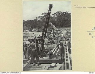 BOUGAINVILLE. 1945-05-01. SAPPERS OF 15 FIELD COMPANY, ROYAL AUSTRALIAN ENGINEERS, WORKING ON THE CONSTRUCTION OF A NEW AUSTPANEL BRIDGE OVER THE PURIATA RIVER WATCH A MOBILE CRANE REMOVE LAUNCHING ..