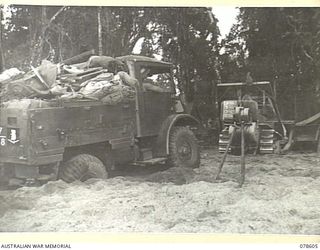 BOUGAINVILLE ISLAND. 1945-01-24. TROOPS OF HEADQUARTERS, 7TH INFANTRY BRIGADE USING A BULLDOZER TO EXTRICATE A HEAVILY LOADED TRUCK BOGGED ON THE BEACH