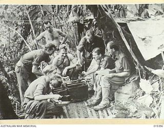 1943-08-04. NEW GUINEA. ON A SITE CUT ON THE SIDE OF A MOUNTAIN, THIS KITCHEN SUPPLIED HOT MEALS TO ALLIED TROOPS ADVANCING ON MUBO. LEFT TO RIGHT: PTE. LES. WOOLLEY, OF FOOTSCRAY, VIC., PTE. LES ..