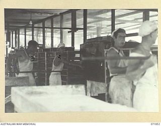 LAE, NEW GUINEA. 1944-03-30. BAKERS OF THE 8TH FIELD BAKING PLATOON "RUNNING" (PLACING THE BREAD IN THE OVENS) AT THE BAKEHOUSE. LEFT TO RIGHT: VX147395 PRIVATE (PTE) E. V. BOYD; V39233 PTE K. A. ..