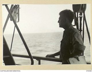 AT SEA. 1944-10-07. NX214 MAJOR F.A. HEDBERG, ARMY MEDICAL CORPS, GAZES PENSIVELY AT THE SHORES OF NEW BRITAIN FROM THE DECK OF THE DUTCH TROOPSHIP "SWEARTENHONDT"