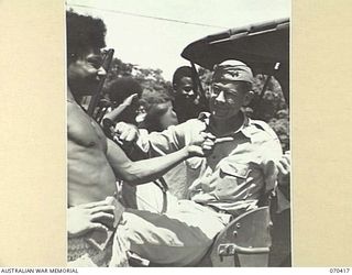 PORT MORSBY, PAPUA, NEW GUINEA, 1944-02-14. CAPTAIN EDGAR L. TIDWELL, THE AMERICAN RADIO LIAISON OFFICER ATTACHED TO "9PA" AUSTRALIAN BROADCASTING COMMISSION BROADCASTING STATION, ASKS FRIENDLY ..