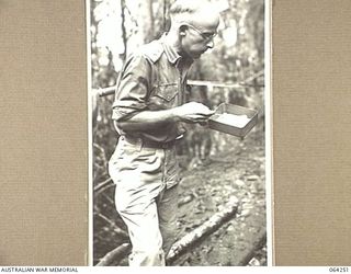 FINISTERRE RANGES, NEW GUINEA. 1944-01-23. VX104251 CAPTAIN C.R. COPLAND, MEDICAL OFFICER OF THE 2/9TH INFANTRY BATTALION EATING FROM A DIXIE AT A FORWARD REGIMENTAL AID POST