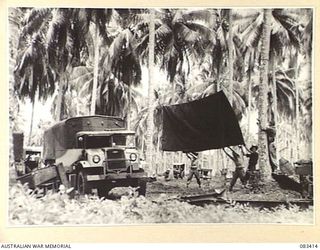 AITAPE AREA, NEW GUINEA, 1944-11-12. TROOPS OF 135 BRIGADE WORKSHOP POSITIONING ONE OF THE MACHINE SHOP TRUCKS UNDER COVER DURING THE ESTABLISHMENT OF CAMP