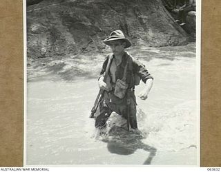 FARIA RIVER, RAMU VALLEY, NEW GUINEA. 1944-01-18. VX206699 GUNNER A. T. TAYLOR OF THE 2/4TH FIELD REGIMENT FORDING THE FAST FLOWING FARIA RIVER ON HIS WAY TO THE FORWARD POSITIONS