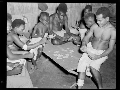 View of young Bougainville Island men and boys playing cards within a medical centre, North Solomon Island group