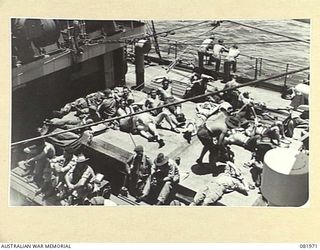 AT SEA. 1944-10-22. TROOPS OF HEADQUARTERS FIRST ARMY ABOARD THE SS TAROONA, RELAXING AND SUNBATHING ON THE NO. 2 HATCH DURING THEIR MOVEMENT TO NEW GUINEA