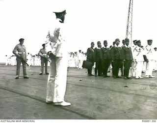 NEW BRITAIN, 1945-09-06. OFF RABAUL A JAPANESE SURRENDER PARTY STANDS ON THE FLIGHT DECK OF HMS GLORY FLANKED BY MEMBERS OF THE SHIP'S COMPANY. (RNZAF OFFICIAL PHOTOGRAPH.)