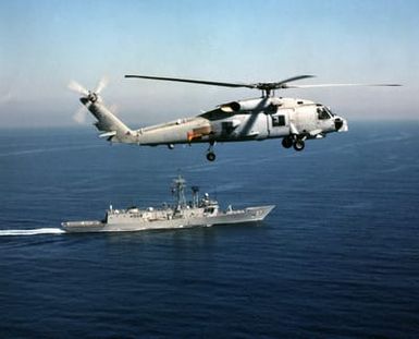 Aerial of a US Navy (USN) SH-60B Seahawk, Helicopter Antisubmarine Squadron Light 41 (HSL 41), Seahawks, Naval Air Station North Island (NASNI) flies by the USN long hull version of the Oliver Hazard Perry Class Frigate USS CROMMELIN (FFG 37), Pearl Harbor, Hawaii (HI)