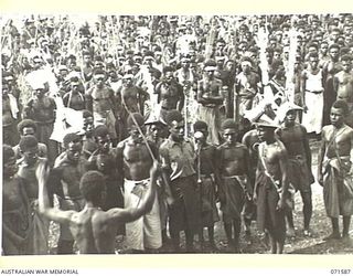 SONG RIVER, FINSCHHAFEN AREA, NEW GUINEA. 1944-03-26. ALL NATIVES GATHERED AROUND WHILE THEIR CHOIR SANG "NEARER MY GOD TO THEE", AND "GOD SAVE THE KING", IN ENGLISH, DURING FESTIVITIES HELD AT THE ..