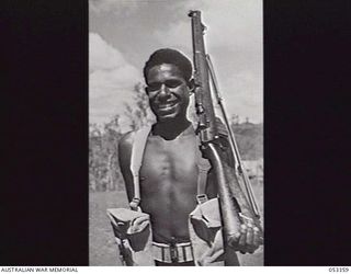BISIATABU, NEW GUINEA. 1943-07-01. R.57 PRIVATE MADAIO, FROM DARU, A 15 YEAR OLD RECRUIT OF THE 1ST PAPUAN INFANTRY BATTALION. THIS RECRUIT'S NUMBER IS ONLY A TEMPORARY ONE, WHICH IS GIVEN TO ALL ..
