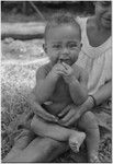 Smiling baby chews on finger, looks at camera