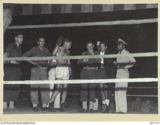 BOSLEY FIELD, TOROKINA, BOUGAINVILLE. 1945-04-21. CONTESTANTS AND OFFICIALS CHATTING IN THE RING IMMEDIATELY BEFORE THE MAIN BOUT BETWEEN KID DELANEY, 2 AUSTRALIAN WATERCRAFT COMPANY (1), AND V.A. ..