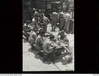 MOMOTE, LOS NEGROS ISLAND, ADMIRALTY ISLANDS. 1944-03-08. RAAF KITTYHAWK PILOTS HAVING THEIR LUNCH AT BENCHES AND TABLES IN A PARTLY ERECTED CREW-ROOM NEAR THE AIRSTRIP. THEY ARE READY TO DROP ..