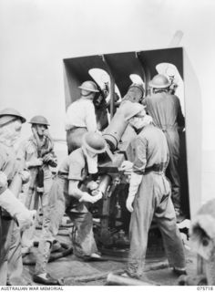 The gun crew firing the 4 inch Mark XIX gun on a Mark XXIII mounting aboard the RAN Corvette Geelong, while on convoy duty off the New Guinea coast