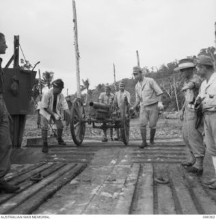 KAIRIRU ISLAND, NEW GUINEA, 1945-09-08. JAPANESE SOLDIERS WHEELING 75 MM MOUNTAIN GUN ONTO A BARGE. THE WEAPONS ARE BEING MOVED, UNDER HQ 6 DIVISION SUPERVISION, TO WEWAK. HANDING OVER OF WAR ..