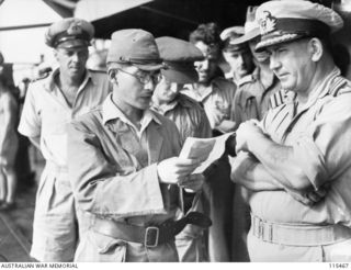 A Japanese surrender envoy reading a message from his commander, Lieutenant-General (Lt-Gen) M Kanda, Commander, 17th Japanese Army, to Commander A E Fowler, RAN, representing Lt-Gen S G Savige, ..